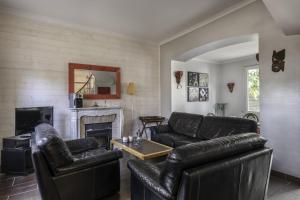 ein Wohnzimmer mit schwarzen Ledermöbeln und einem Kamin in der Unterkunft Villa Les Libellules pour 8 à 9 personnes in La Baule