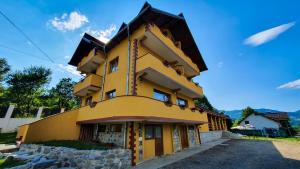 żółty budynek z dachem gambrel w obiekcie Pensiunea Annalisa w mieście Corbeni