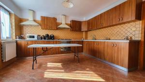 a kitchen with wooden cabinets and a table in it at Pensiunea Annalisa in Corbeni