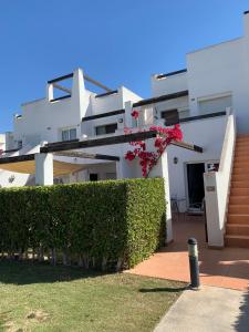 une maison blanche avec une haie devant elle dans l'établissement Naranjo 7 - N565 - 2 bathrooms Apartment in Alhama de Murcia Golf Resort, à Alhama de Murcia