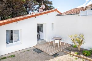 a white house with a wooden deck and a table at Séjour détente à Bretignolles-sur-Mer pour 5 personnes in Brétignolles-sur-Mer