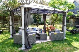 a gazebo with a couch and chairs in a yard at 4 Sterne Ferienhaus "Zum Weiher" mit E-Ladestation in Allenbach