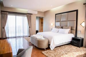 a bedroom with a large white bed and a large window at Schimper View Boutique Guest House in Louis Trichardt