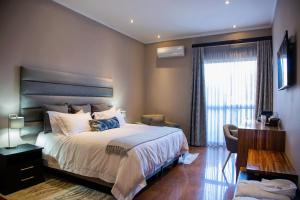 a bedroom with a bed and a desk and a window at Schimper View Boutique Guest House in Louis Trichardt