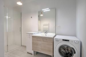 a white bathroom with a washing machine and a sink at Charmant appartement pour 4, remblai de Pléneuf in Pléneuf-Val-André