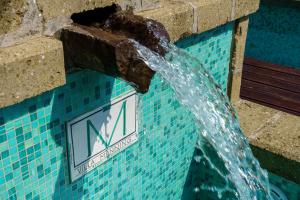 una fontana in una piscina con orologio di Villa Manning Relais a Sorrento