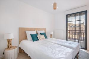 - une chambre blanche avec un grand lit et des oreillers bleus dans l'établissement La plage de Val Andre au pied de l appartement, à Pléneuf-Val-André