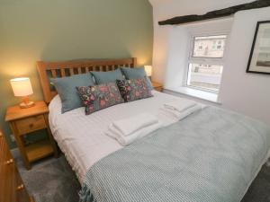 Honey Pot Cottage في لانكستر: غرفة نوم بسرير ومخدات ونافذة