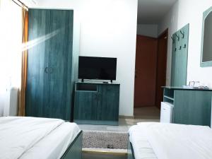 ein Schlafzimmer mit zwei Betten und einem Fernseher an der Wand in der Unterkunft Pensiunea Confort in Suceava
