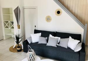 sala de estar con sofá negro y almohadas blancas en Maison avec terrasse à 50 m de la mer en Pornic