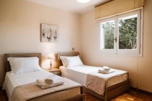 two beds in a room with a window at Villa Butterfly - Heated Pool, Jacuzzi, Sauna, Gym in Corfu Town +32 photos