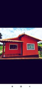 a red house with two windows in a yard at Acomodação chalé entre capitolio e escarpas do lago in Capitólio