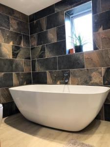 a white bath tub in a bathroom with a window at Lower Farm Lodge in Stowmarket