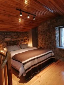 um quarto com uma cama num quarto com tectos em madeira em Casa Encantada - Alvoco da Serra em Alvoco da Serra
