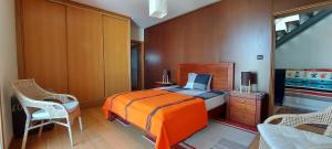 een slaapkamer met een oranje bed en 2 stoelen bij Casa do Mar in Costa Nova