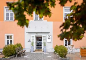 un edificio blanco y naranja con un banco delante en JUFA Hotel Judenburg, en Judenburg