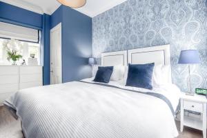 セント・アンドルーズにあるDeluxe Penthouse Apartment w Roof Terraceの青い壁のベッドルーム(白いベッド1台付)