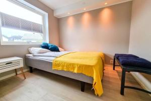 a bedroom with a bed with a yellow blanket and a window at Aurora Central Apartment, Bodø in Bodø