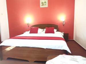 une chambre avec un grand lit aux murs rouges dans l'établissement Pensiunea ODN, à Scheia