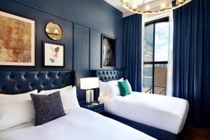 two beds in a room with blue walls at The Grady Hotel in Louisville