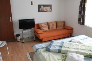 a living room with an orange couch and a flat screen tv at Zimmer Steger in Gnas