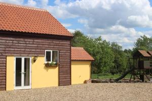 un edificio con un tobogán junto a un parque infantil en Little Oaks en Stowmarket