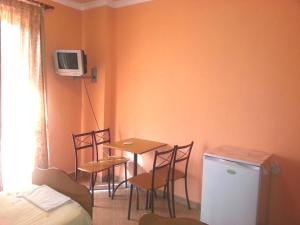 a room with a table and chairs and a table and a tv at Hotel Palma in Durrës