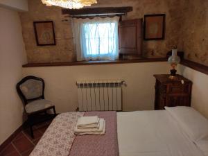 um quarto com uma cama, uma cadeira e uma janela em La Antigua casa del cartero em Roda de Eresma