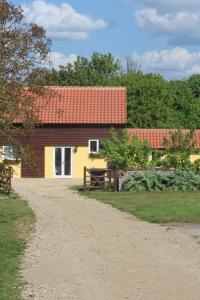 una casa con techo rojo y un camino de tierra en Little Oaks en Stowmarket