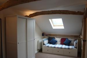a room with a couch in a attic with a window at Little Oaks in Stowmarket