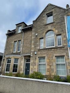 a brick house with windows and a blue sky at Premier 3 Bed Flat D in Broxburn