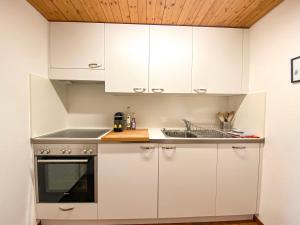 貝特默阿爾卑的住宿－Studio Apartment Alpine Lodge (36m2) - Bettmeralp - Ski in/out - South facing, overlooking the Alps，厨房配有白色橱柜和水槽