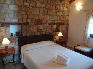 a bedroom with a bed and a stone wall at Niriides in Galaxidi