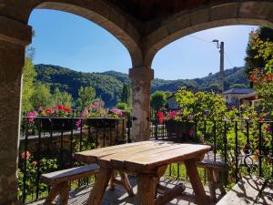 a wooden picnic table on a balcony with flowers at Casa Rural El Puente in Polvoredo