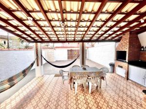 een patio met een tafel en stoelen onder een houten plafond bij Casa Aconchegante a 200 mts da Praia da Maranduba in Ubatuba