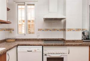 a white kitchen with a stove and a sink at Chalet Harley Denia in Denia