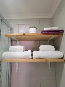 a wooden shelf with towels on it in a bathroom at Tiny House Faro in Faro