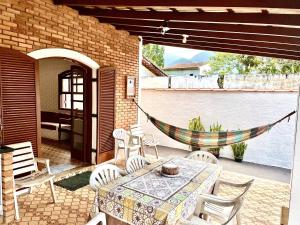 een patio met een tafel en stoelen en een hangmat bij Casa Aconchegante a 200 mts da Praia da Maranduba in Ubatuba