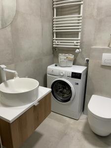 a bathroom with a washing machine and a sink at Yoisho Apartment in Kołobrzeg