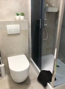 a bathroom with a white toilet and a shower at Yoisho Apartment in Kołobrzeg