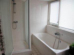 een witte badkamer met een bad en een douche bij Park Nest in Zeewolde +15 foto's