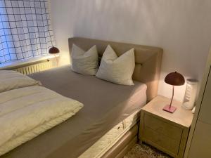 un letto con cuscini bianchi e un tavolo con una lampada di Eremitageparken a Kongens Lyngby