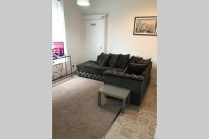 a living room with a black couch and a table at Arthur Apartment in Hawick +1 photo