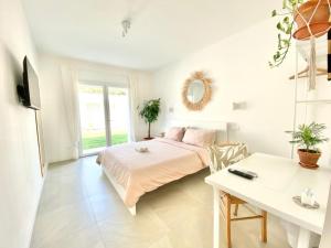 a white bedroom with a bed and a desk at Pathos Guest House in Quarto dʼAltino