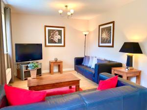 uma sala de estar com um sofá azul e uma televisão em Aylesbury Contractor & Staycation Home em Aylesbury