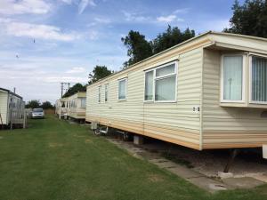 a row of mobile homes parked in a yard at Spacious caravan with DG, CH & veranda in Skegness