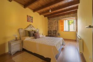 een slaapkamer met een bed in een kamer met gele muren bij A Casa da Charca - Casa rural con jardín in Pontevedra