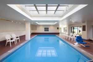 布齊耶比利牛斯2000的住宿－卡勒旅館及套房酒店，一个带椅子和桌子的大型室内游泳池