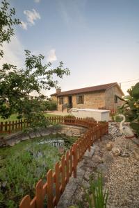 una valla frente a una casa con un estanque en A Casa da Charca - Casa rural con jardín en Pontevedra