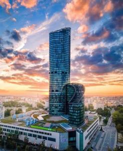 wysoki budynek w mieście o zachodzie słońca w obiekcie 30th+ Floor Apartments in Sky Tower we Wrocławiu